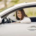 happy elegant woman sitting in car smiling at camera